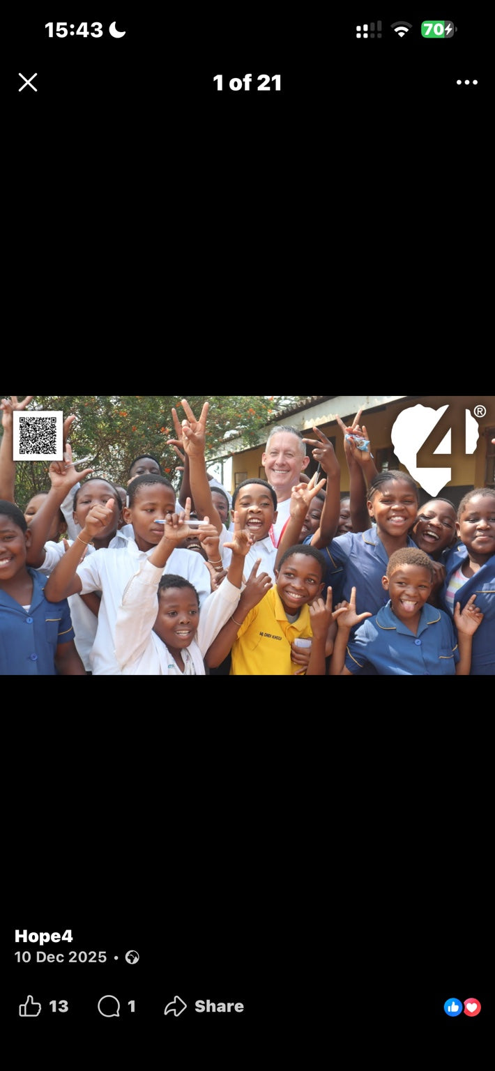 Chris smiling with a group of children during Hope4 community work.