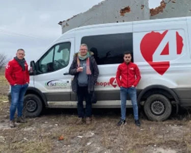 Three people standing beside a Hope4 relief vehicle in Moldova.