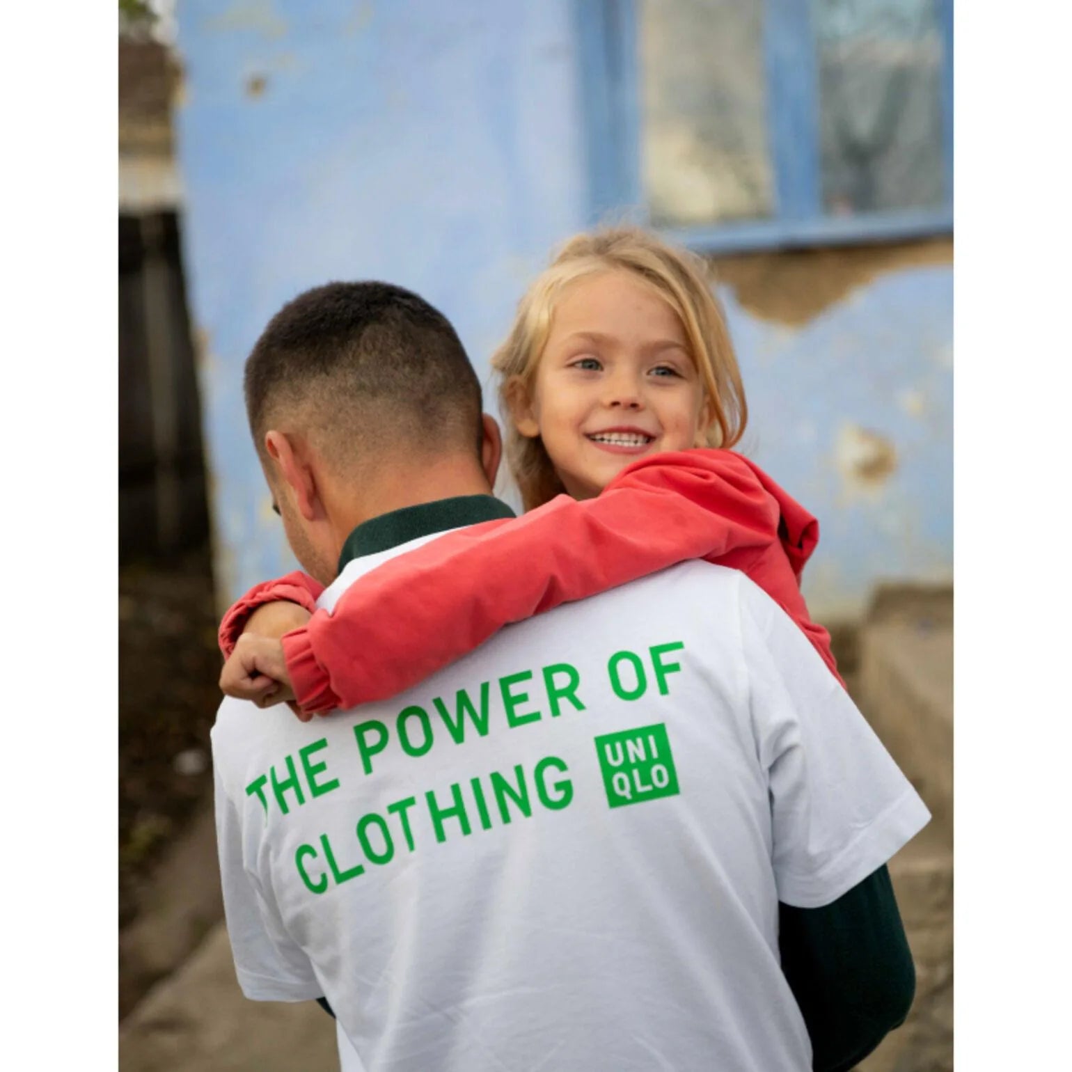 A smiling child in a red coat being held by a volunteer during the Moldova visit.
